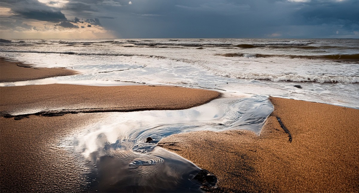 Пятна мазута на пляже. Иллюстрация создана «Кавказским узлом» с помощью ИИ в программе Photoshop