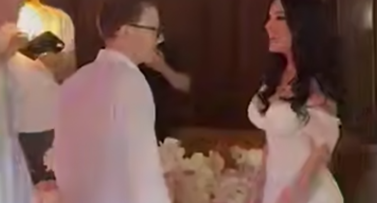 Альберт Каноков с девушкой на фоне букета. Стоп-кадр видео https://t.me/mash_gor/8107 от 12.06.25.