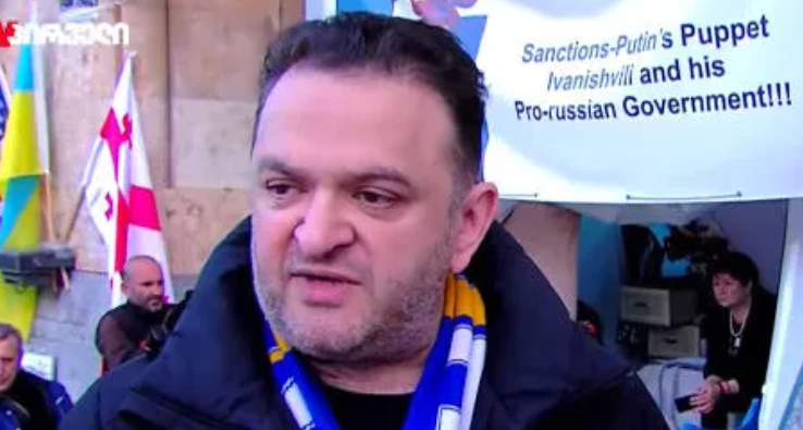 Гедеван Попхадзе у здания парламента Грузии. Скриншот фото "Интерпрессньюс" от 28.10.25, https://www.interpressnews.ge/ru/article/171490-gedevan-popkhadze-i-aktivisty-nachinaiut-golodovku-u-zdaniia-parlamenta