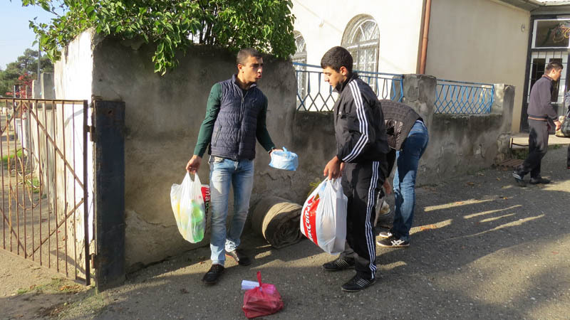 Парни собирают вещи и грузят в авто.